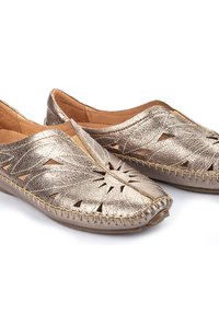 Chaussures en cuir doré métallisé avec des motifs découpés, des coutures de style mocassin et un bout arrondi. Doublure intérieure douce pour plus de confort.