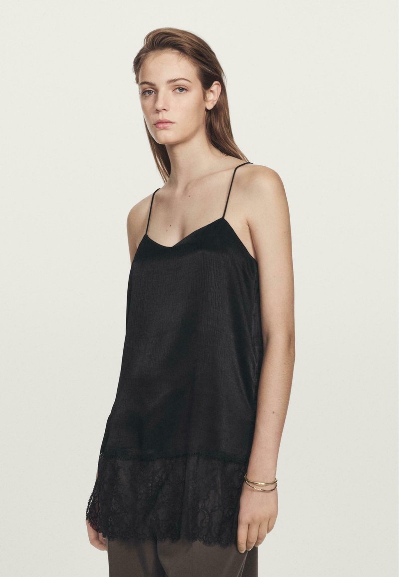 Top in satin nera con spalline sottili e scollatura a V, caratterizzato da un tessuto testurizzato e profilo in pizzo sul bordo.