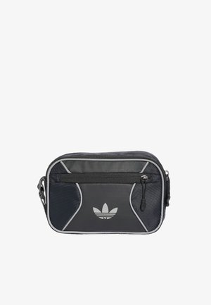 Mała czarno-szara torba na ramię Adidas z przednią kieszenią na zamek i logo na przednim panelu, na białym tle.