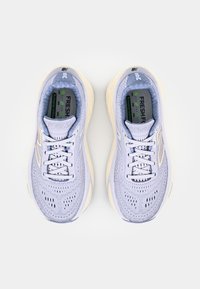 Lys lilla joggesko med mesh-overside, flate snører, polstret såle og små perforeringer for ventilering. Har merkevare på tungen.