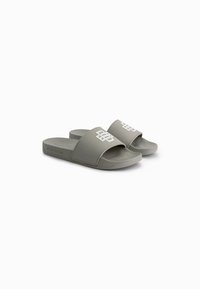 Gray rubber slide sandals with wide strap featuring a white logo, textured footbed, and flat sole for comfort and ease of wear.