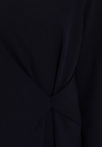 Dark navy fabric with a smooth texture features a twisted detail at the waist, creating a subtle draped effect.
