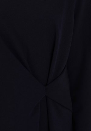 Mørk sømandsblå stof med en glat tekstur har en snoet detalje ved taljen, der skaber en subtil draperingseffekt.