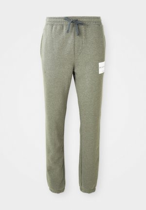 Heather-grå tapered sweatpants med elastiskt midjeband, dragsko, sidofickor, ankelfållar och en liten vit varumärkesetikett på höger lår.