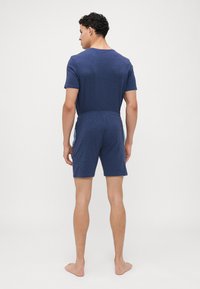 Mörkblå kortärmad T-shirt och matchande shorts i mjukt, strukturerat tyg. Plaggen har ett elastiskt midjeband och en avslappnad passform.