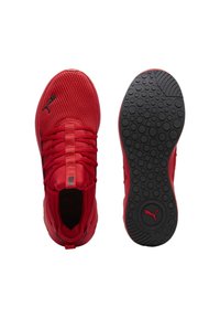 Des chaussures de sport rouges avec une tige en maille, des lacets plats et une semelle en caoutchouc noir texturé présentant des motifs circulaires et un logo.