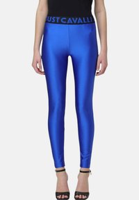 Blauwe satin legging met een zwarte "JUST CAVALLI" tailleband; strakke pasvorm, glanzende textuur, enkellang, gecombineerd met zwarte gespenhakken.