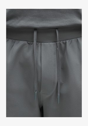 Hallid dressipüksid elastse vöökohaga ja nööriga. Omavad pehmet kangatekstuuri, õmmeldud detaile ja esitaskuid.