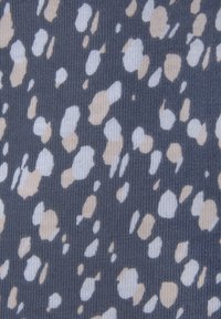 Kangaskuvio, jossa on tummanharmaa tausta ja epäsäännöllisiä, hajallaan olevia laikkuja beige- ja valkoisena. Pintarakenne näyttää uritetulta.
