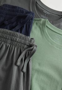 Drei Kleidungsstücke: ein graues T-Shirt, ein grünes T-Shirt und marineblaue Shorts. Alle haben eine weiche, glatte Textur und elastische Bündchen.