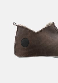 Bruine leren slipper met een fuzzy binnenvoering. Heeft een laag uitgesneden ontwerp, topstiksels en een rond zwart logo aan de zijkant.