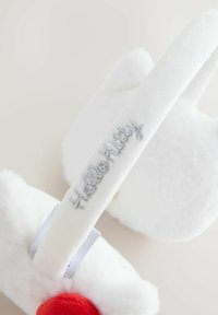 White plush slippers with a soft texture, featuring a red accent and silver "Hello Kitty" embroidery on the strap. Round design.