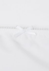 Garbato in tessuto bianco con un bordo testurizzato e un piccolo fiocco decorativo bianco nella parte superiore. Texture liscia, aspetto morbido.