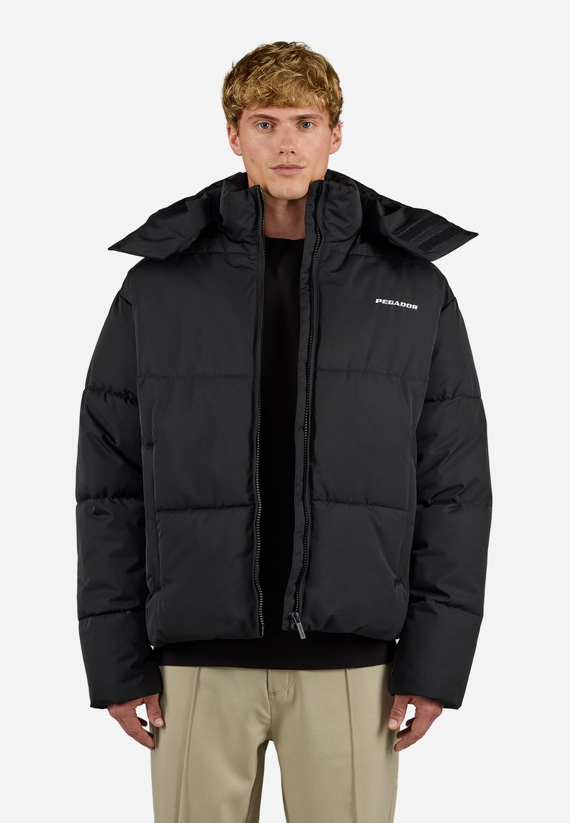 Črna puffer jakna z visokim ovratnikom, zadrgo in quilted oblikovanjem. Narejena iz gladkega materiala, z logotipom na prsih.