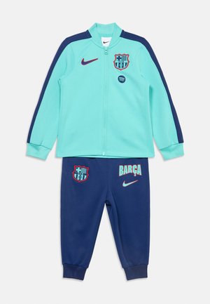 Survêtement Nike Barcelona bleu clair et bleu marine avec veste zippée et pantalon avec logos du club et texte "BARÇA".