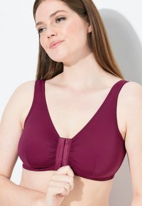 Burgunderfarbenes Bra mit weichem Stoff, V-Ausschnitt-Design, breiten Trägern und verstellbarem Frontverschluss. Mit subtilen Rüschen und gewellten Kanten.