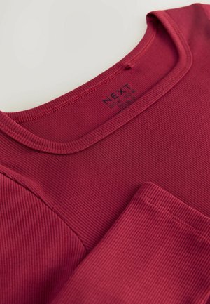 Vínový žebrovaný top s dlouhým rukávem, kulatým výstřihem a kapsou na prsou, vyrobený z texturované látky s viditelným prošíváním.