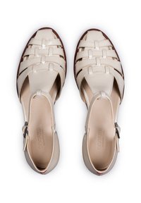 Sandali in pelle beige chiaro con design intrecciato, aperture sui lati e chiusura con fibbia. L'esterno è marrone e testurizzato.