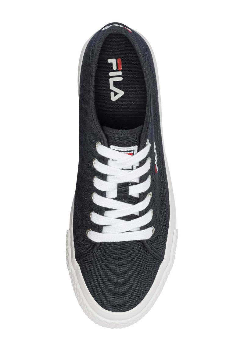 Zapatilla de lona negra con cordones blancos, suela de goma y logotipo de Fila en la lengüeta. Presenta un diseño sencillo y una textura suave.