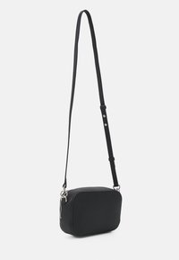 Black crossbody bag made of textured material with a rectangular shape, adjustable strap, and silver hardware accent at the zipper.
