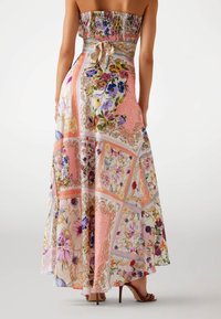 Colorful maxi dress with a smocked bodice, floral patchwork design in pink, purple, and cream, and a tied detail at the waist.