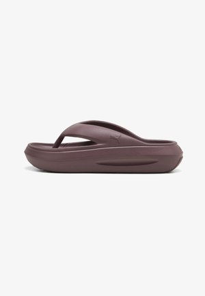 Einzelne braune gepolsterte Flip-Flop-Sandale mit dicker Sohle und strukturiertem Fußbett, Seitenprofil auf weißem Hintergrund.