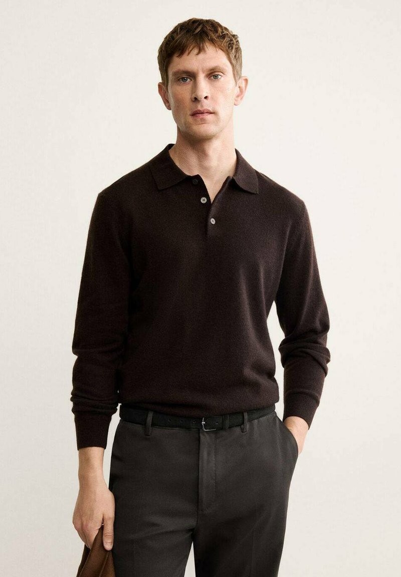 Maglione polo a maniche lunghe di colore marrone scuro, con colletto e tre bottoni. Indossato con pantaloni neri, caratterizzati da una texture liscia e un design aderente.