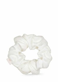 Biały satynowy scrunchie o teksturowanym, marszczonym wzorze, z bezszwowym okrągłym kształtem i małą metką przymocowaną do niego.