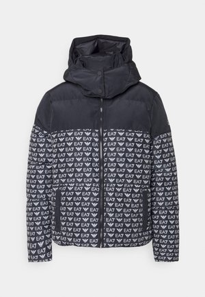 Veste matelassée noire avec fermeture éclair et capuche, affichant un motif répété du logo blanc EA7 sur la partie inférieure et une section supérieure noire unie.