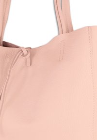 Roze leren totebag met een gestructureerde afwerking, voorzien van twee schouderbanden en een ingesnoerde sluiting. Versterkte stiksels langs de randen.