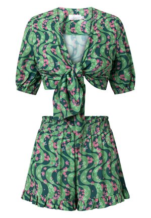 Sada zeleného květinového potisku obsahující zkrácený top se zavazováním vpředu a nabíranými rukávy, spolu s odpovídajícími vysoko pasovými kraťasy s volánkovým lemem.