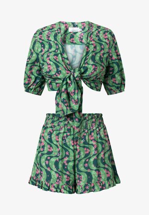 Sada zeleného květinového potisku obsahující zkrácený top se zavazováním vpředu a nabíranými rukávy, spolu s odpovídajícími vysoko pasovými kraťasy s volánkovým lemem.