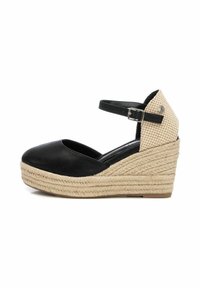 Zapato de cuña de esparto negro con suela de yute trenzado, con punta redondeada, correa en el tobillo y un patrón de cuadros texturizado en el tacón.
