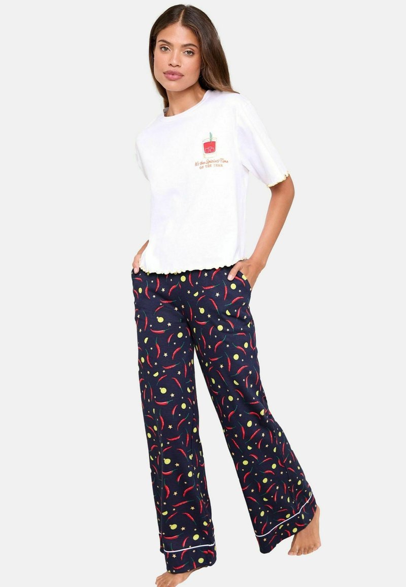 Tricou alb din bumbac cu un design brodat în roșu și verde, asortat cu pantaloni de pijama bleumarin cu modele colorate de fructe și spirală.
