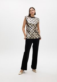 Sequined top with metallic circular sequins in gold and silver tones, paired with black wide-leg trousers and gold pointed heels.