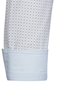 Polsino di una camicia a maniche lunghe azzurro chiaro con un tessuto a motivo che presenta piccoli diamanti. Il tessuto ha una sottile trama e accenti blu a contrasto.