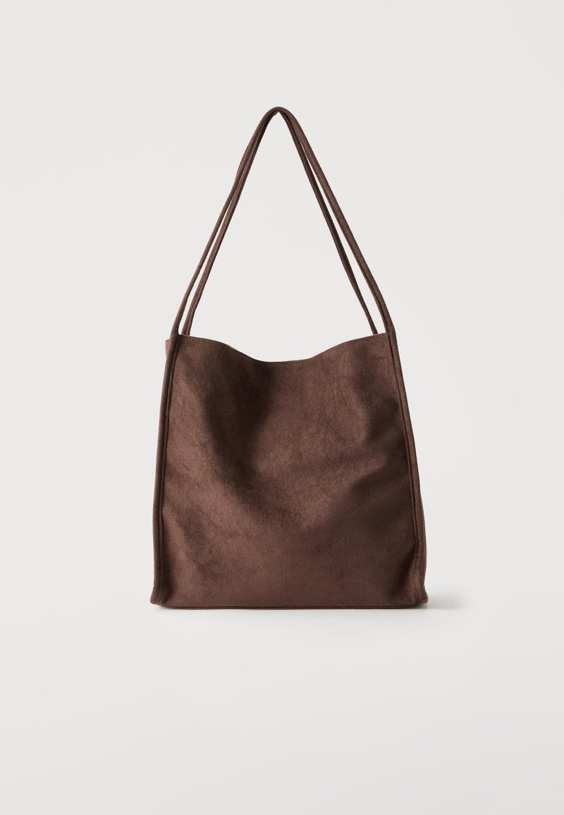 Sac à épaule en daim marron avec doubles fines bretelles, forme rectangulaire simple et texture douce sur un fond clair uni.