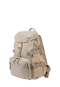 Zaino beige chiaro con pattina superiore, fibbia frontale, tasca frontale con zip, tasche laterali in rete e spallacci imbottiti.