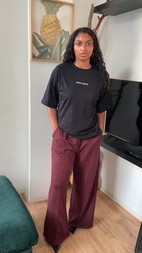 Zwarte katoenen T-shirt met witte tekst, gecombineerd met bordeaux brede broekspijpen. Gladde stof met scherpe, op maat gemaakte randen en puntige zwarte hakken.