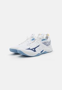 Witte sportschoenen met lichtblauwe accenten, voorzien van een bovenwerk van mesh, een slank design, veters en een opvallend donkerblauw logo aan de zijkant.