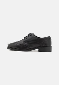 Scarpe da uomo in pelle nera con finitura liscia, dettagli brogue, punta arrotondata e tacco basso. Presentano chiusura con lacci e accenti testurizzati.