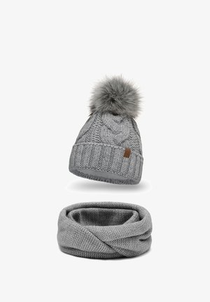Grey knitted beanie with textured cables and a faux fur pom-pom, paired with a matching grey infinity scarf, both soft and seamless.