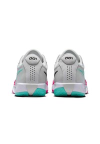 Baskets de sport blanches avec des accents roses et turquoise, tige en mesh, col rembourré et semelles en caoutchouc texturé. Présente le numéro "001" sur le talon.