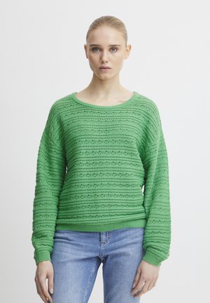 Pulover verde tricotat, cu un design texturat și cu dungi, cu mâneci late și un decolteu rotund, asociat cu blugi de culoare albastru deschis.