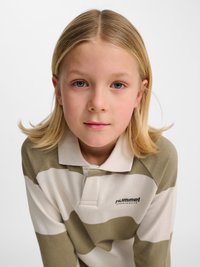 Barn med skulderlangt blondt hår iført en beige og hvid stribet Hummel sportspolo, som kigger direkte på kameraet.