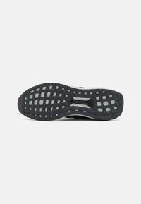 Black athletic shoe sole with a textured grip pattern, featuring prominent circular lugs and a reinforced central section.