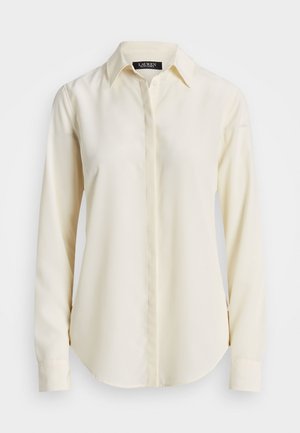 Camisa de manga longa, com gola, na cor creme. Feita de um tecido suave, com fecho de botão à frente e bainha arredondada. Design simples e clássico.