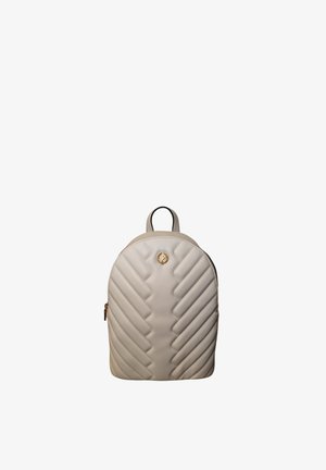 Piccolo zainetto beige trapuntato con parte superiore arrotondata, cerniera dorata e piccolo emblema dorato sulla parte anteriore, isolato su sfondo bianco.