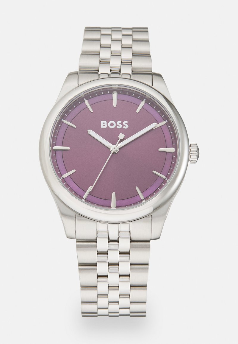 Sudraba nerūsējošā tērauda pulkstenis ar apaļu korpusu, purpursarkanu ciparnīcu, sudraba rādītājiem un tīkla aproces dizainu. Logo redzams ciparnīcā.