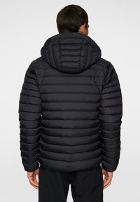 Svart puffjacka med huva, med en kviltad design och horisontella ränder, elastiska ärmslut och en mjuk textur.